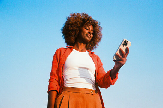 Woman holding smartphone against blue sky film photo