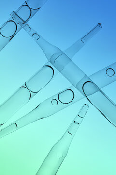 Several glass pipettes with liquid on gradient blue backdrop.