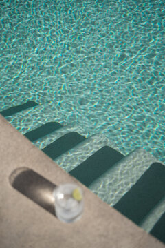 defocused glass with a transparent clear drink by the poolside