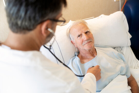 Doctor examining senior patient with stethoscope in hospital