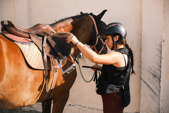 Horsewoman putting the reins on the horse
