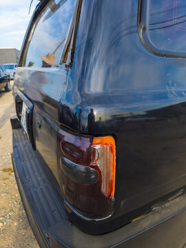 Close-up of Damaged Taillight on Dark SUV Reflecting Sky