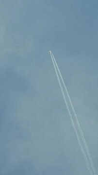 passenger airplane flying high in sky leaving contrail vertical