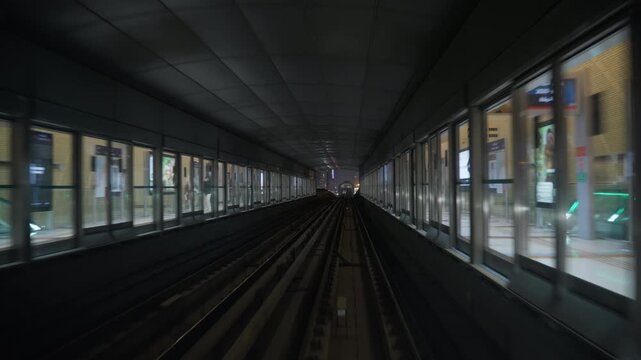 DUBAI, UAE - AUGUST 29, 2026: Dubai Metro train moves through a covered station in Dubai UAE, passing platform screen doors and waiting passengers at night