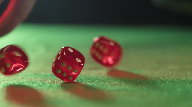Close up of a player hand throwing two red dice on a green felt casino table during a game of craps, gambling and betting concept with luck and chance.