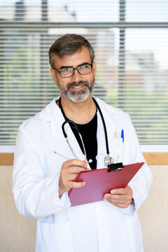 Doctor holding clipboard smiling in hospital setting