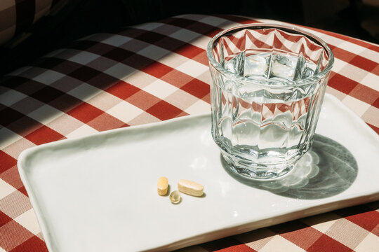 Glass of water with multivitamins on white tray