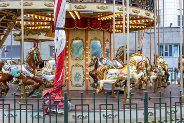 Vintage merry go round carousel with colorful horses in city © Mila