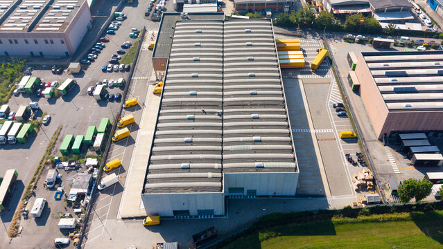 San Giuliano Milanese, Italy - 05 September 2026: Aerial view of the Filiale DHL Express facility, showing a large warehouse, yellow delivery trucks, and industrial surroundings.