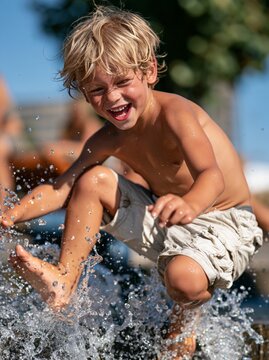 Cheerful child playing outdoors with water, enjoying a refreshing summer day