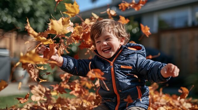 Smiling child throwing fall leaves in a backyard during autumn season