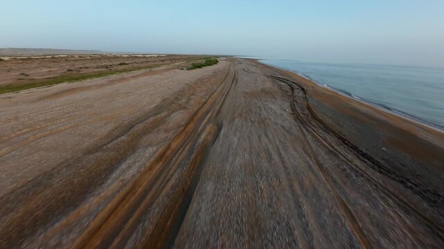 Forward tracking shot along coastal dirt and pebble road