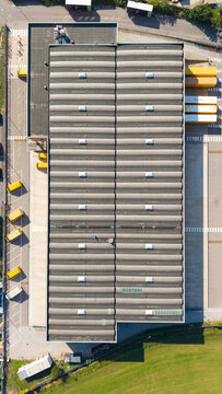 San Giuliano Milanese, Lombardia, Italy - 04 September 2026: Aerial view of the Filiale DHL Express facility with a corrugated metal roof, loading docks, and yellow delivery trucks.