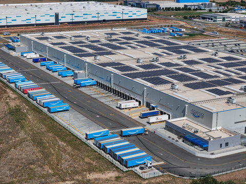 Spinetta Marengo, Italy - 05 September 2026: Aerial view of Amazon distribution centre with numerous blue trailers parked at loading docks and solar panels on the roof.