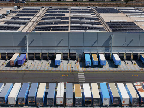 Spinetta Marengo, Piedmont, Italy - 05 September 2026: Aerial view of the Amazon distribution centre with rooftop solar panels, loading docks, and rows of parked semi-truck trailers.