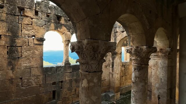 Horizontal camera movement through ancient stone columns, ornate capitals and arches at Alahan Monastery, revealing detailed early Christian architecture.