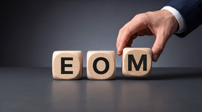 businessman hand placing wooden cube block spelling eom on dark office desk representing end of month financial accounting and audit deadline