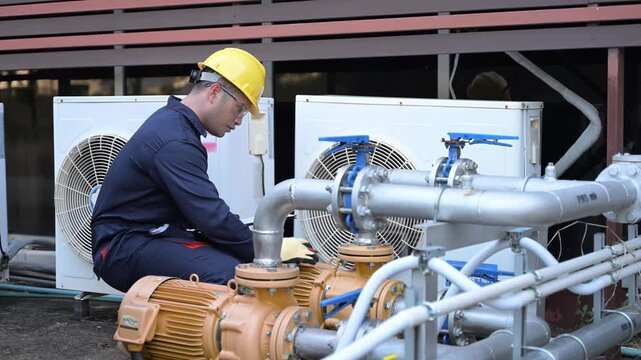Professional engineers inspecting industrial air conditioning system outside. Construction workers checking hvac maintenance with clipboard and toolbox at manufacturing factory site plant.