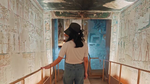 A beautiful tourist wanders inside the tomb of King Seti I, looking for the inscriptions and drawings carved on the walls of the tomb.