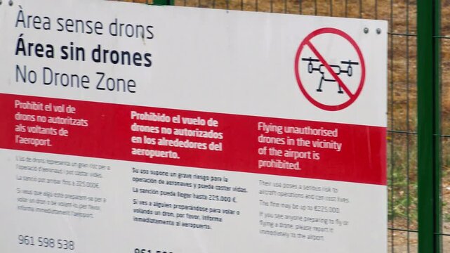 VALENCIA, SPAIN - SEPTEMBER 4, 2026: A warning sign prohibits unauthorized drone flights on the perimeter fence of Valencia Airport operated by Spanish airport manager Aena as camera zooms in