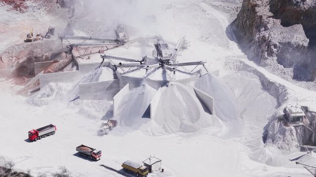Aerial view of a stone quarry and processing plant with crushing machinery, heavy equipment and clouds of dust surrounded by forested hills in North Macedonia.4K ProRes rec.709 D Log m