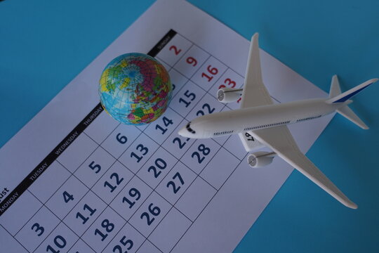 An airplane on a calendar page next to a globe, representing a vacation