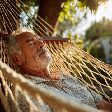 Senior Man Sleeping Peacefully In Net Hammock Outdoors In Garden