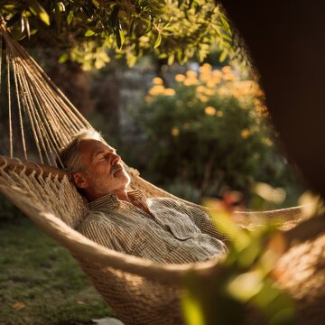 Senior Man Napping In Rope Hammock In Beautiful Summer Garden