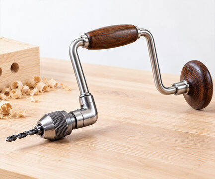 Hand drill with wooden handle on wooden surface, craftsmanship, DIY tools