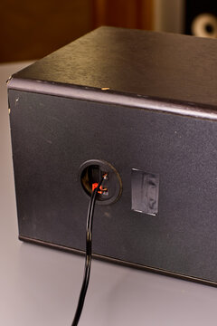 Two hands holding stripped copper wire ends beside electronic enclosure during wiring repair, warm studio lighting with closeup detail of exposed conductor strands