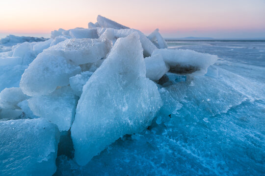 Large ice blocks of sea ice covering a frozen shoreline beneath a winter sky