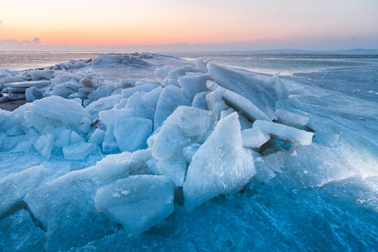 Large ice blocks of sea ice covering a frozen shoreline beneath a winter sky