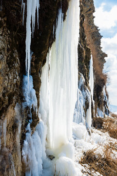 Massive icicles covering a cliff and frozen waterfall in a winter mountain landscape