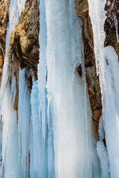 Massive icicles covering a cliff and frozen waterfall in a winter mountain landscape