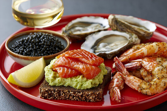 Seafood platter with caviar, oysters and prawns on a red plate