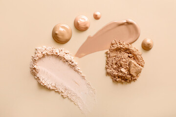 Swatches of different foundations and face powders on beige background, flat lay