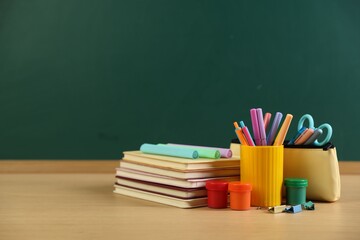 Different stationery on wooden table near chalkboard, space for text © New Africa