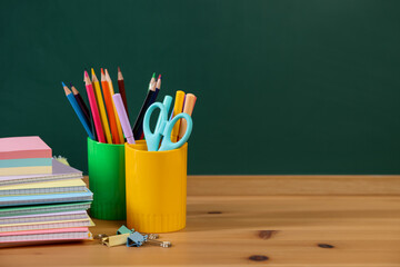 Different stationery on wooden table near chalkboard. Space for text © New Africa