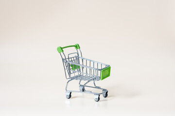 Empty miniature shopping cart on light background with copy space © Anastasiia