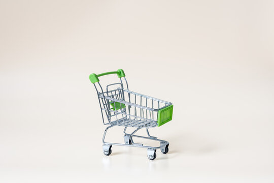 Empty miniature shopping cart on light background with copy space