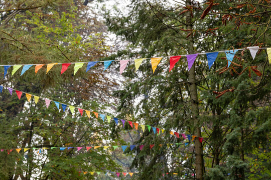 Colorful bunting garlands hanging among trees in a city park