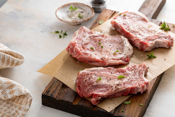 Fototapeta premium Pork chops on a bone with salt, pepper and herbs ready to be cooked