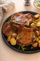 Obraz premium Pork chops on a bone grilled or sauteed served with roasted potatoes on a plate