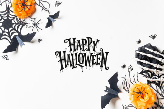 Happy Halloween lettering framed by black and orange roses, spiderwebs, bats and skeleton hands on white, ideal for cards, invitations, posters and seasonal advertising.