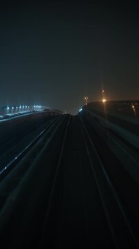 DUBAI, UAE - AUGUST 29, 2026: Dubai Metro train passes an oncoming train on elevated tracks in Dubai UAE at night, with a Samana developer sign beside the route