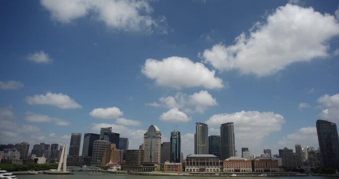 SHANGHAI, CHINA - AUGUST 23, 2026: White cumulus clouds drift over modern skyscrapers along the Huangpu River waterfront in Shanghai China, in timelapse
