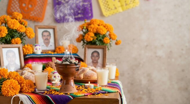 Copal incense burning on traditional Day of the Dead altar. Ofrenda with marigold flowers, candles, portraits and pan de muerto