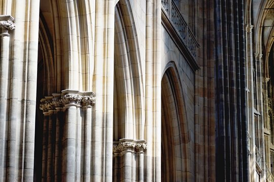 Stunning Gothic interior of St. Vitus Cathedral in Prague. The image highlights towering stone columns with intricate capitals and elegant pointed arches bathed in natural light.