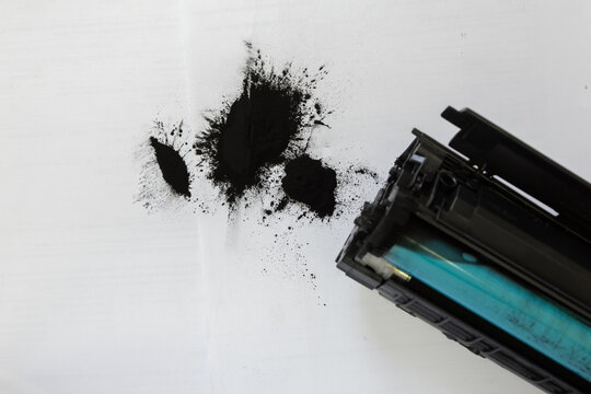 Toner spilled onto the desk from a broken laser printer cartridge.