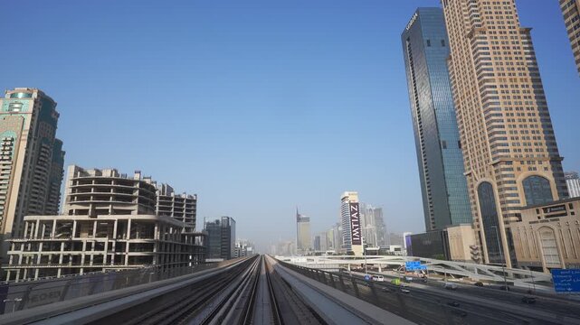 DUBAI, UAE - AUGUST 29, 2026: Dubai Metro travels in slow motion on elevated track past IMAZ tower above highway traffic in Dubai UAE during daytime